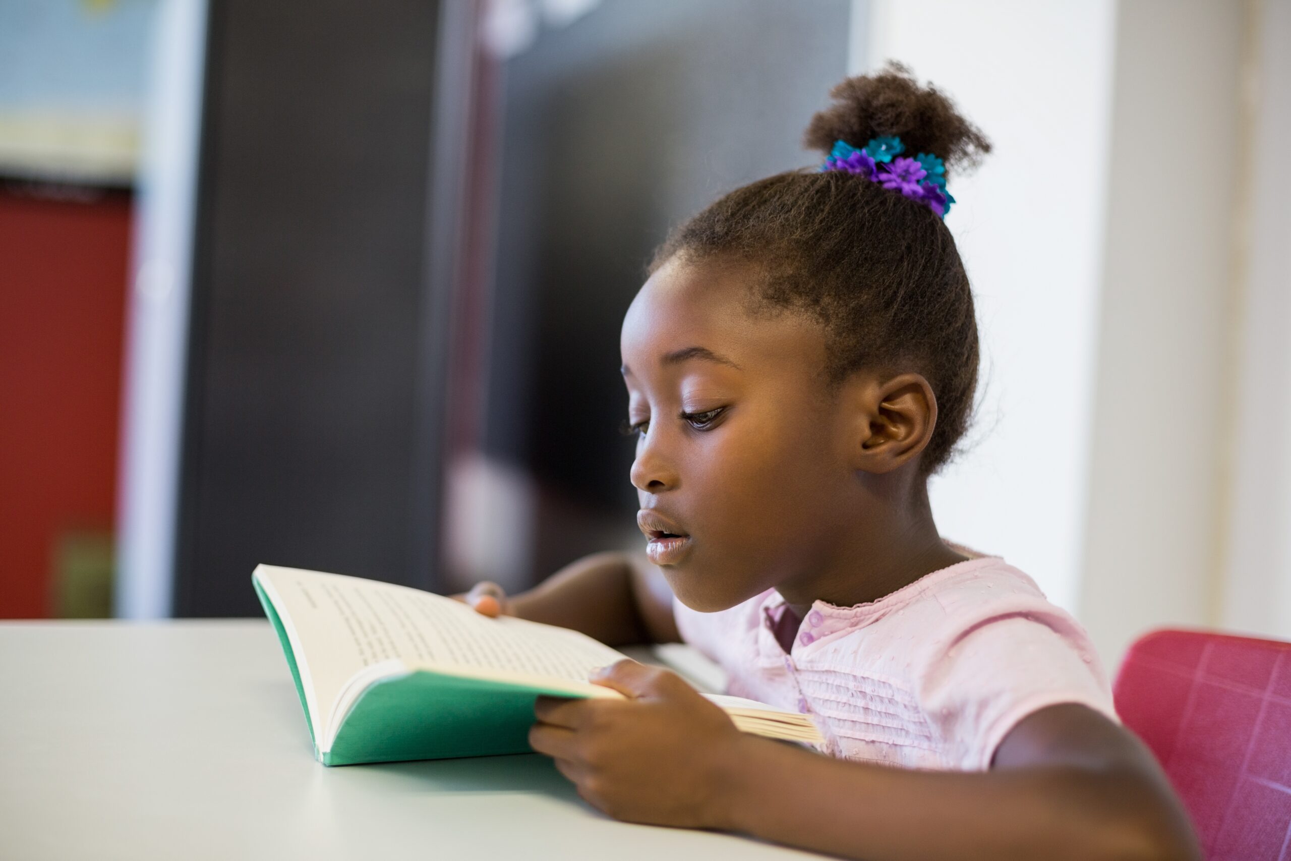 Young girl reading a book at a table